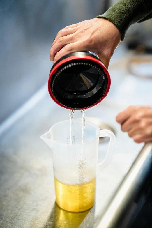 a person pouring yellow liquid into a plastic cup