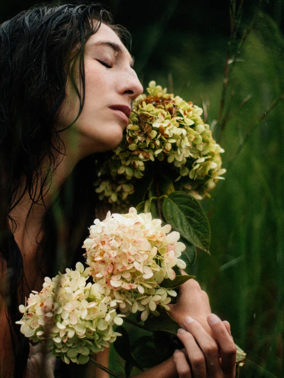 a woman with her eyes closed holding some flowers