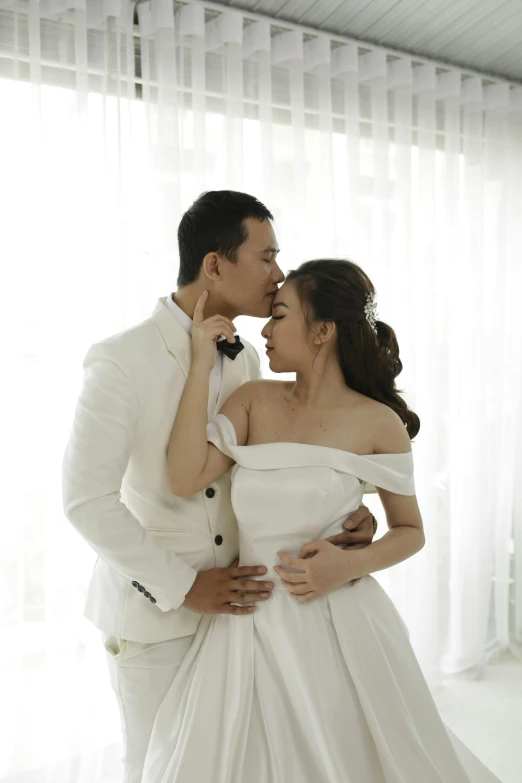 a woman is kissing the neck of a man wearing a white suit