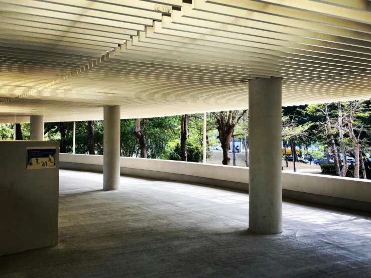 a empty building with lots of pillars, a few windows and trees