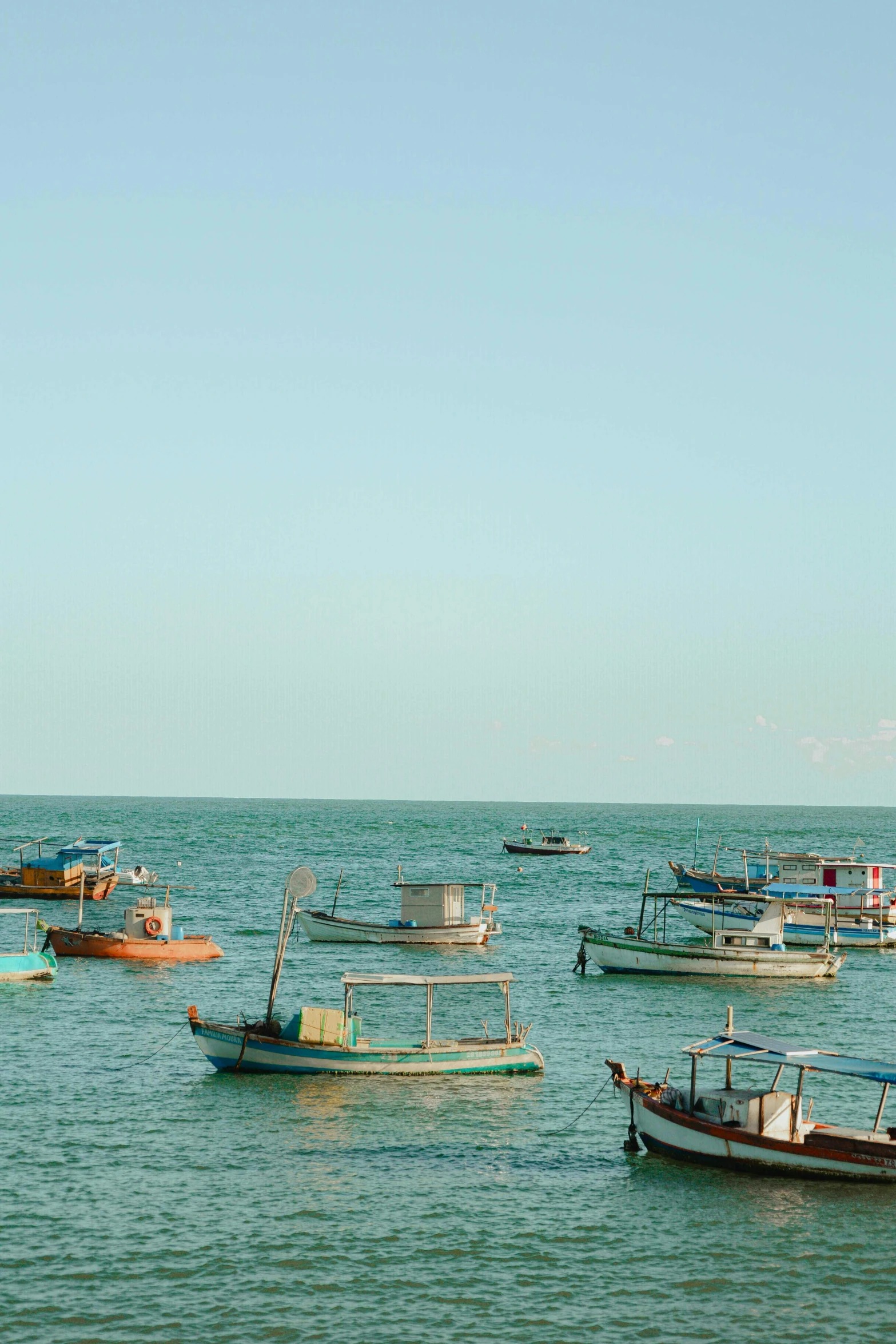 several fishing boats are on the ocean and two people are riding in them