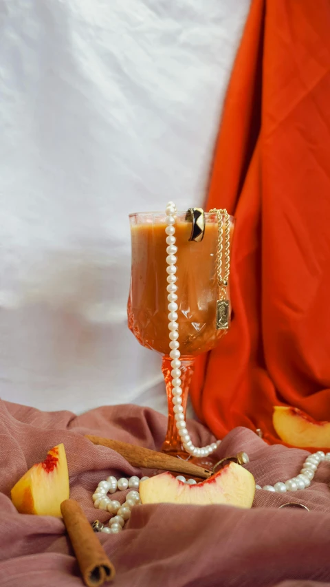 a glass of fruit and an apple slice are on a blanket