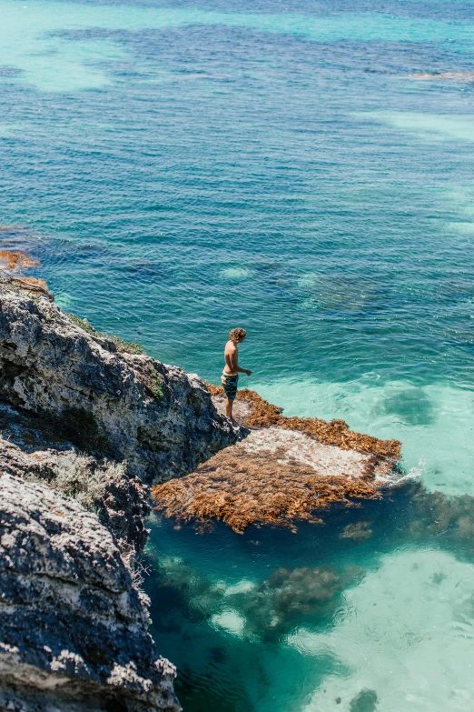 man standing on top of a rocky cliff next to the ocean