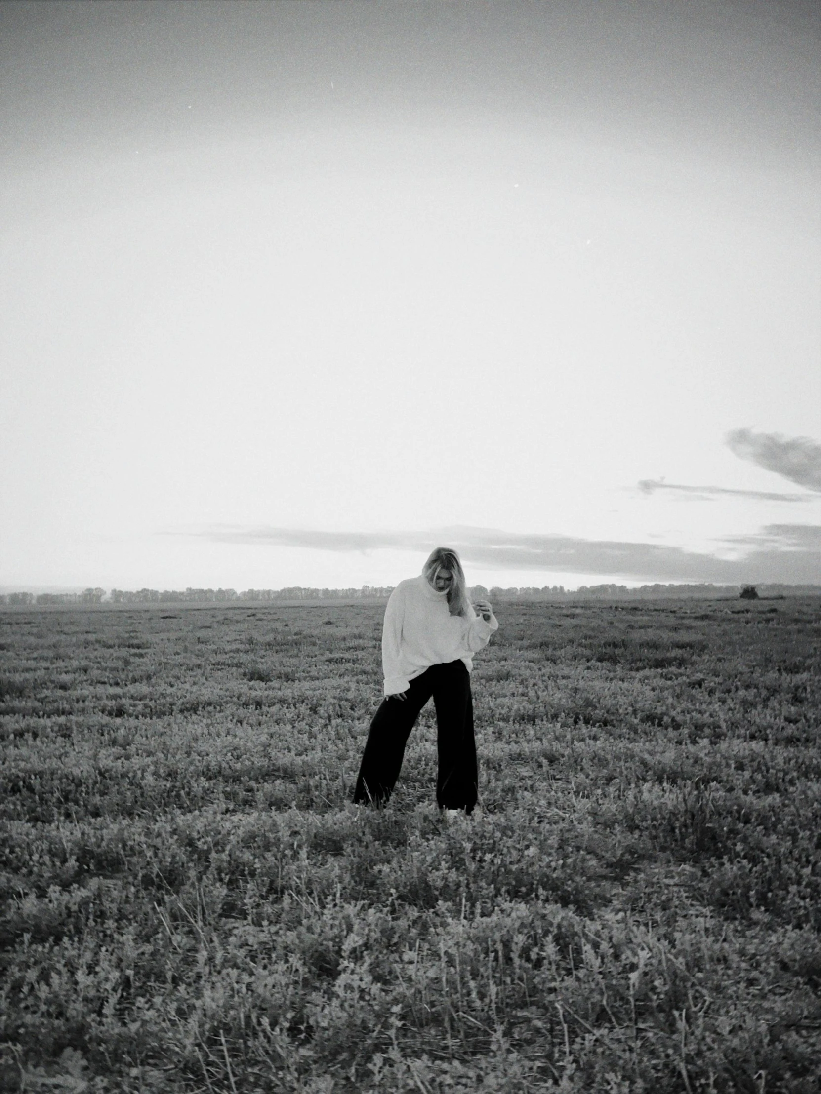 a person with long hair walking through a field