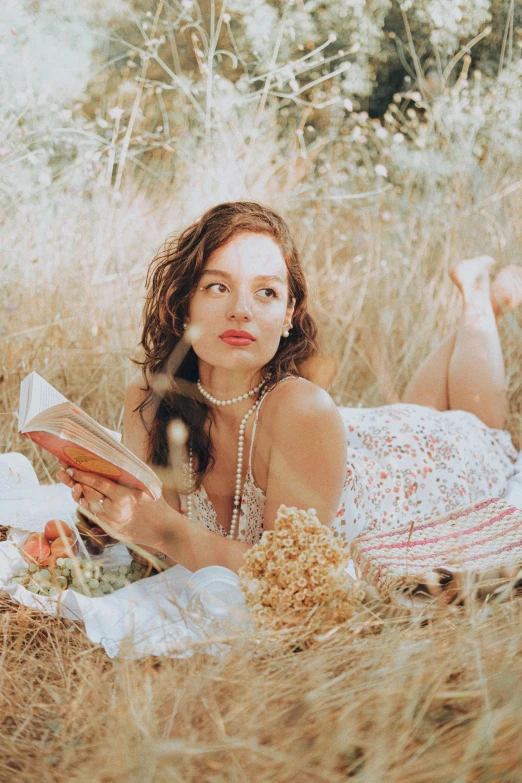 a woman is laying in the grass reading a book