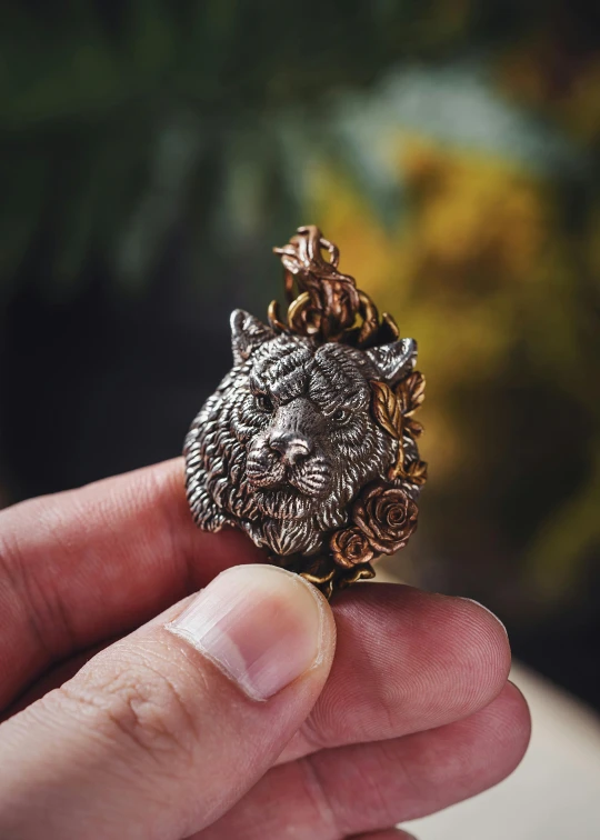 someone holding a tiny gold lion head brooch