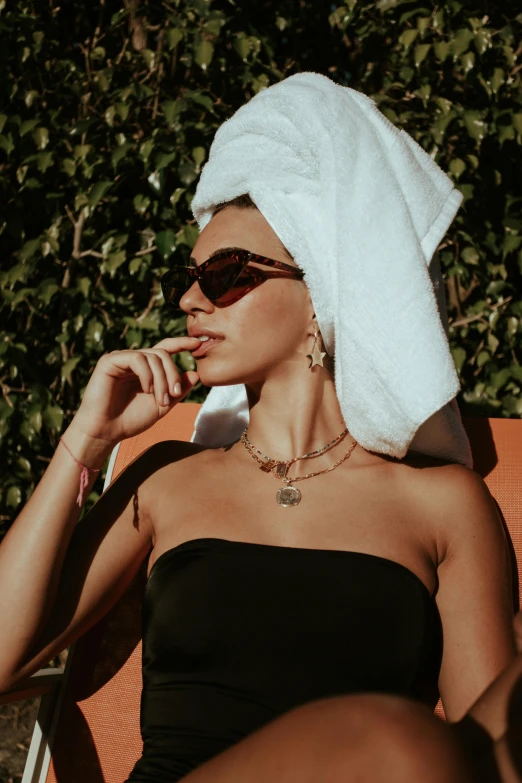 woman in sun glasses and towel on the back of an orange chair