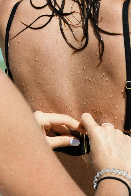 a woman standing next to the ocean holding onto her nails