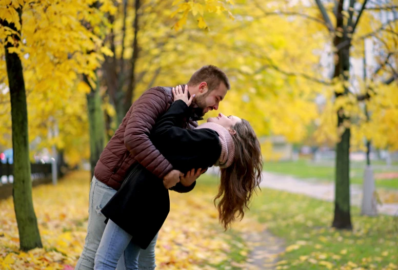 couple emcing in autumn with a leaf filled path