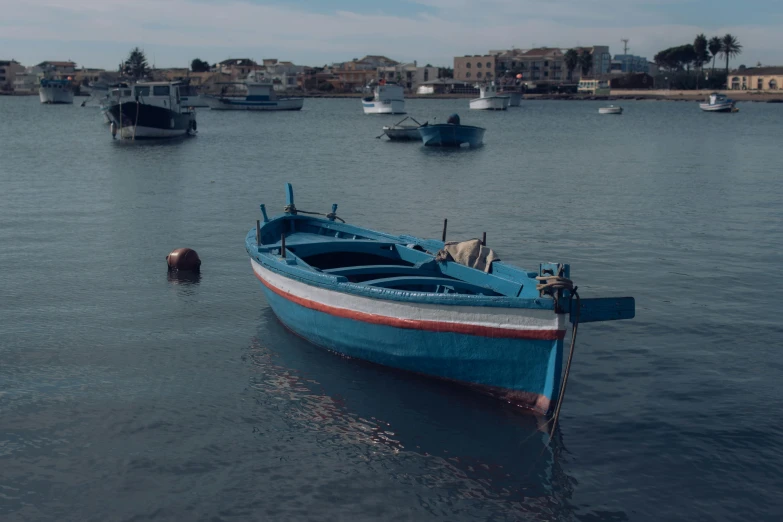 a blue boat floating in the middle of a harbor next to other boats