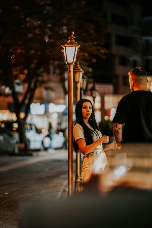 two people standing next to a tall pole with a street light