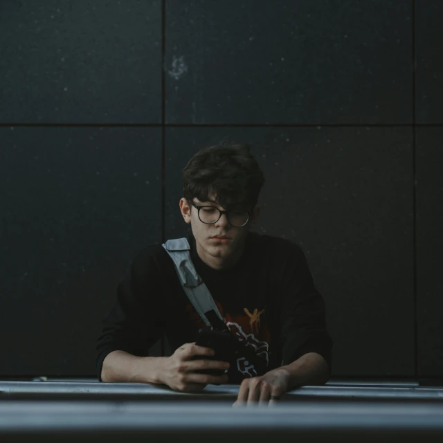 a young man sitting at a table with a pair of glasses in his hand