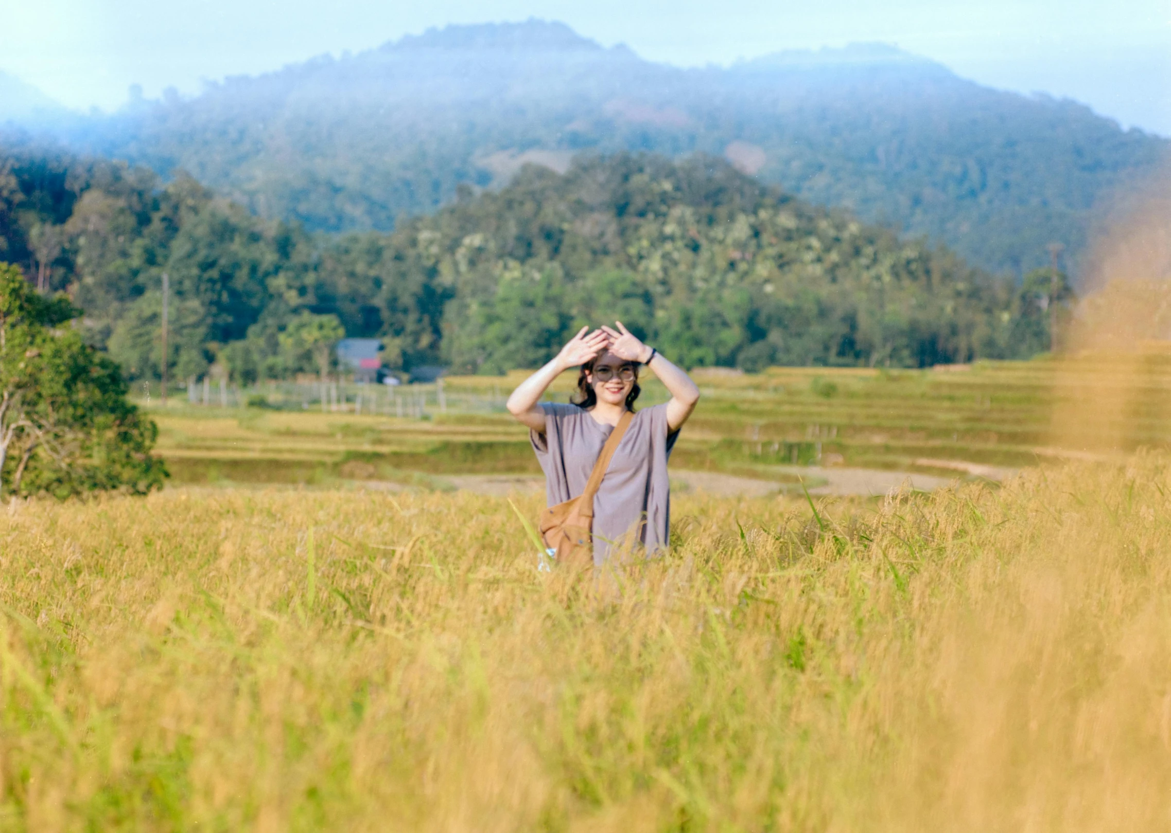 a man in a field looking up at the sky with mountains in the background