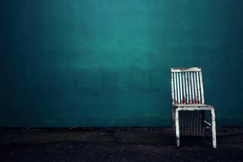 a wooden chair standing in front of a green wall