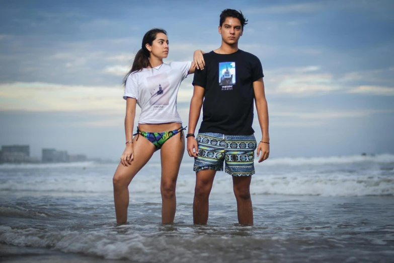 the young couple are standing in the water at the beach