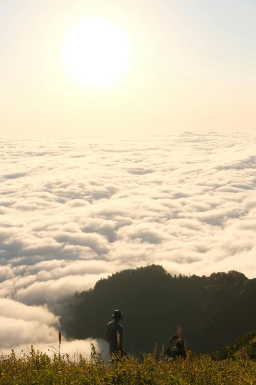 the two people are on top of the mountain above the clouds