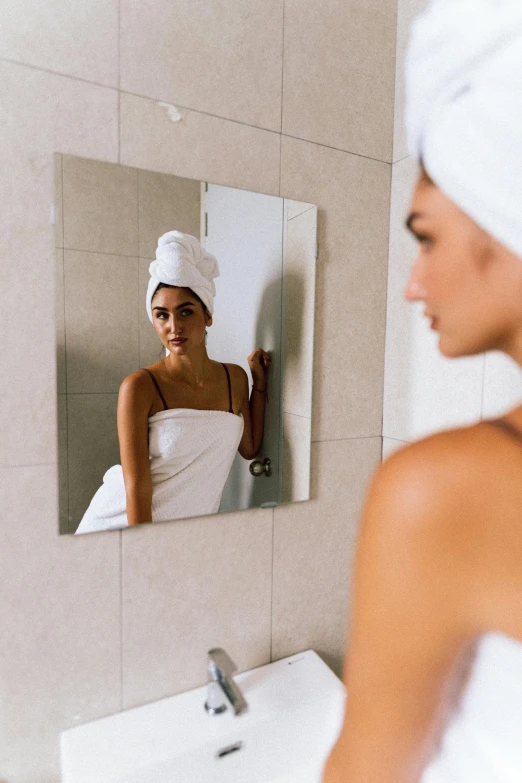 a woman in a white towel is in front of a mirror