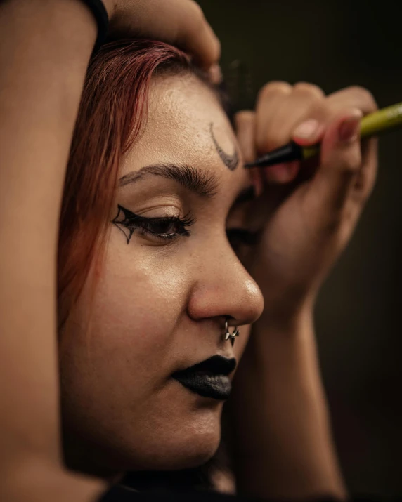 a woman in halloween makeup is holding a cigarette and nose ring