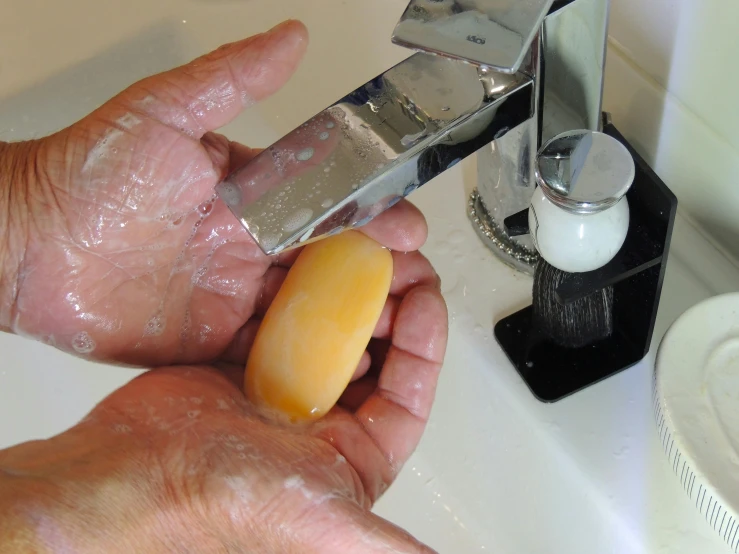 a man washing his face with soap under the faucet