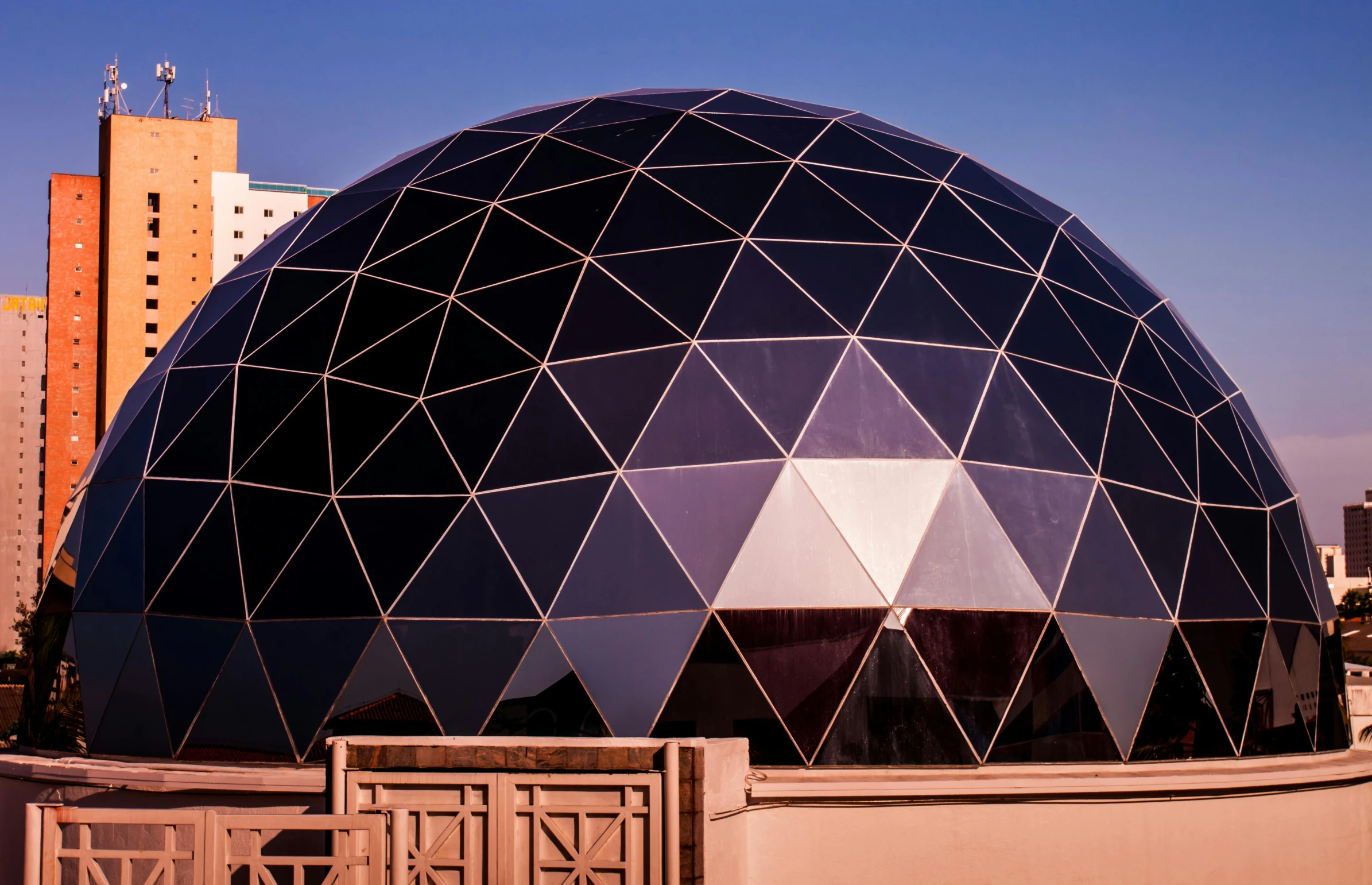 an outdoor dome structure with triangulars in front of a city