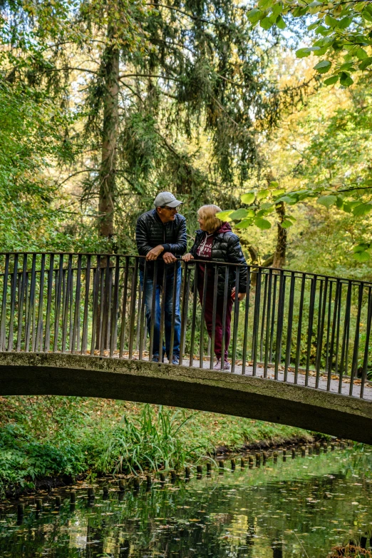 two people walking on the bridge over water