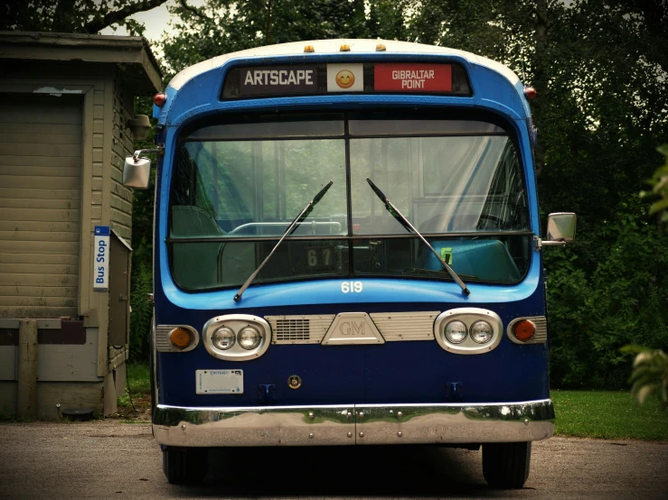 a blue bus is sitting by a garage