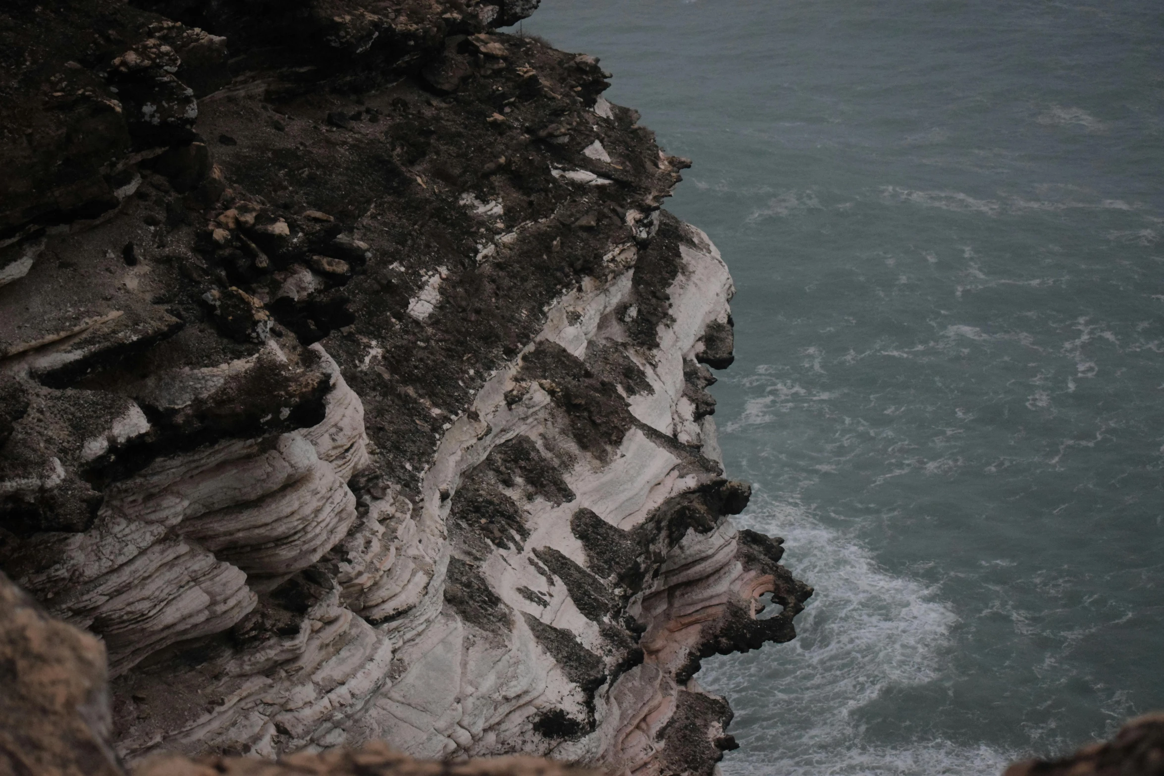 rocks and sea water near a cliff by the ocean