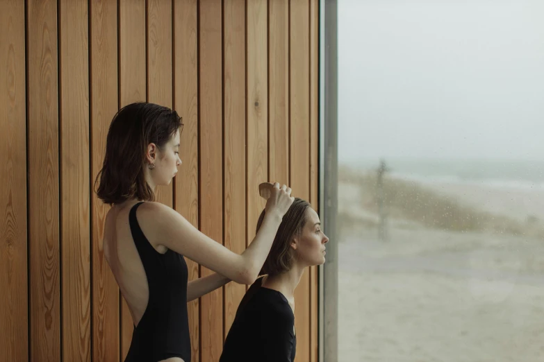 two women are in bathing suits and combing their hair