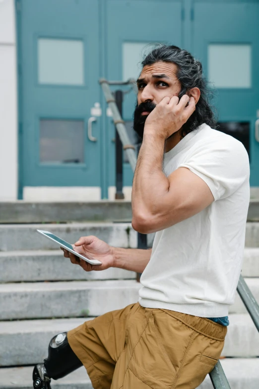 a man with a goatee on the phone with a book in his hand