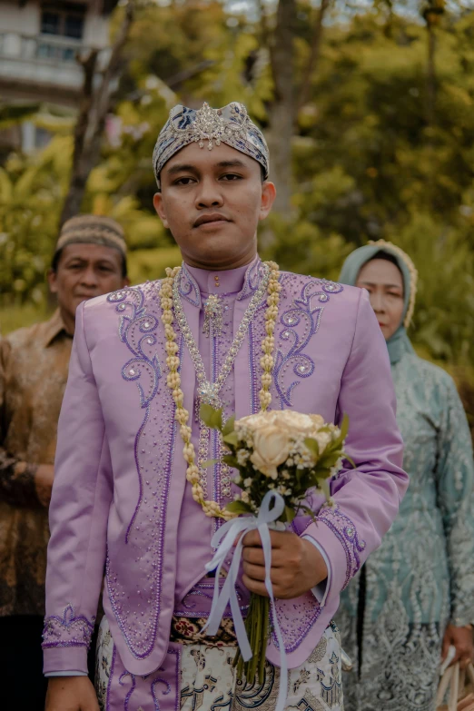 a person in a purple outfit with flowers on the neck and other people around
