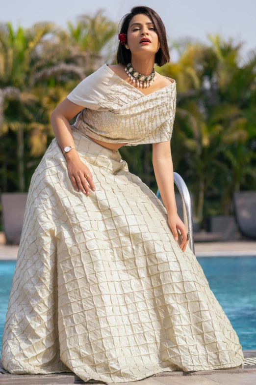 a woman in white dress standing near a pool