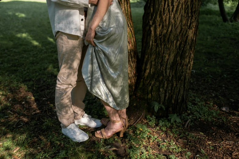 a beautiful woman standing next to a man in front of a tree