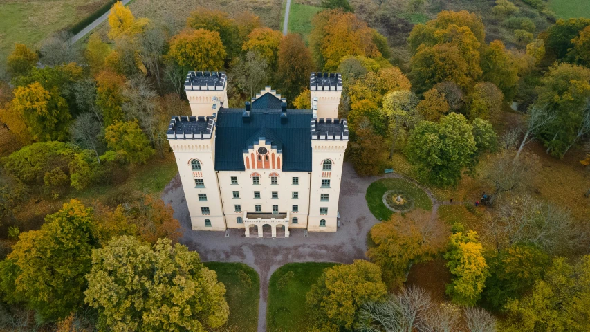 a large castle style building is seen from above in the middle of the fall season
