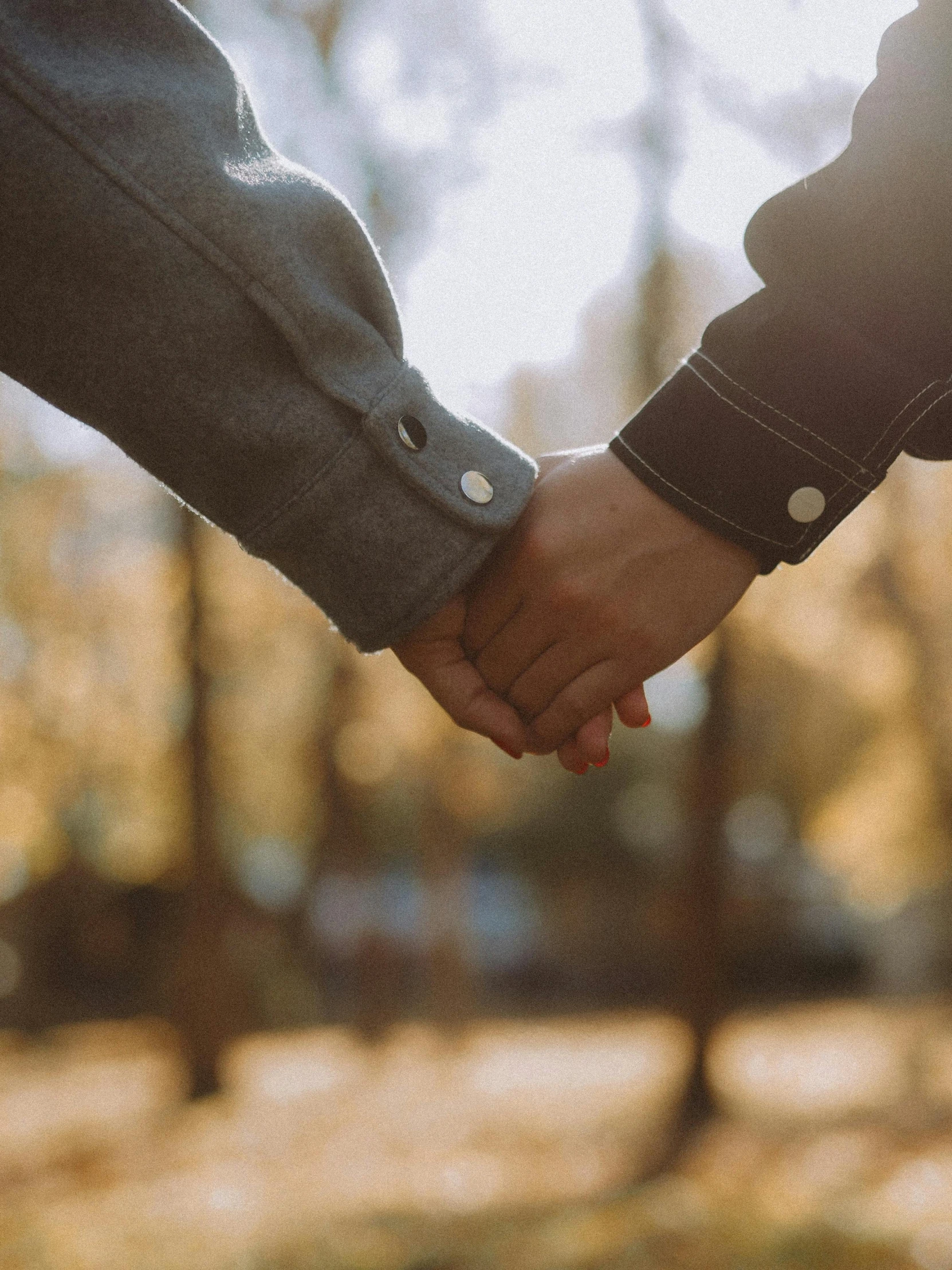 a couple holding hands over a wooden fence