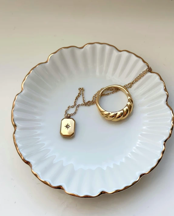 a white and gold plate topped with a small chain