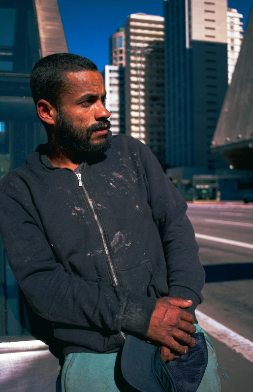 a man looking off to the side with tall buildings in the background