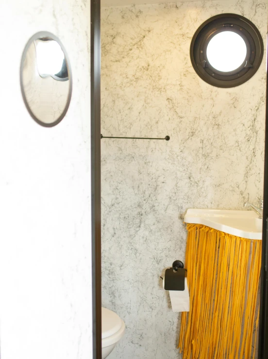 a bathroom with a toilet and mirror next to a window