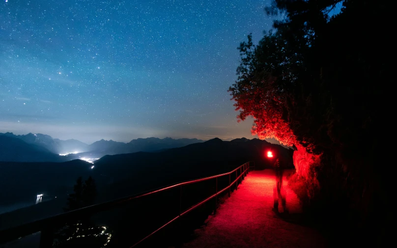 a pathway with lights going down the side and mountains in background