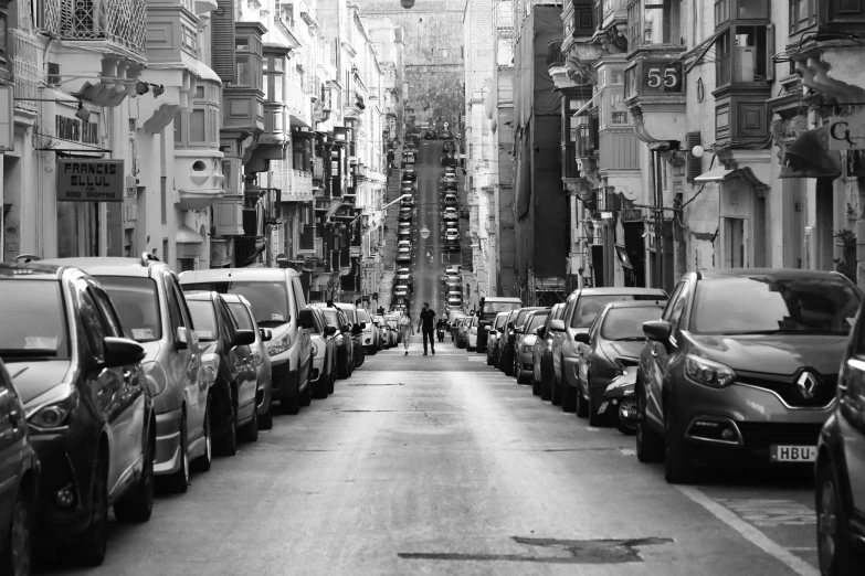 a person in black and white is standing by cars on the street