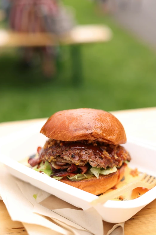 a pulled pork sandwich with lettuce and pickles in a styrofoam container