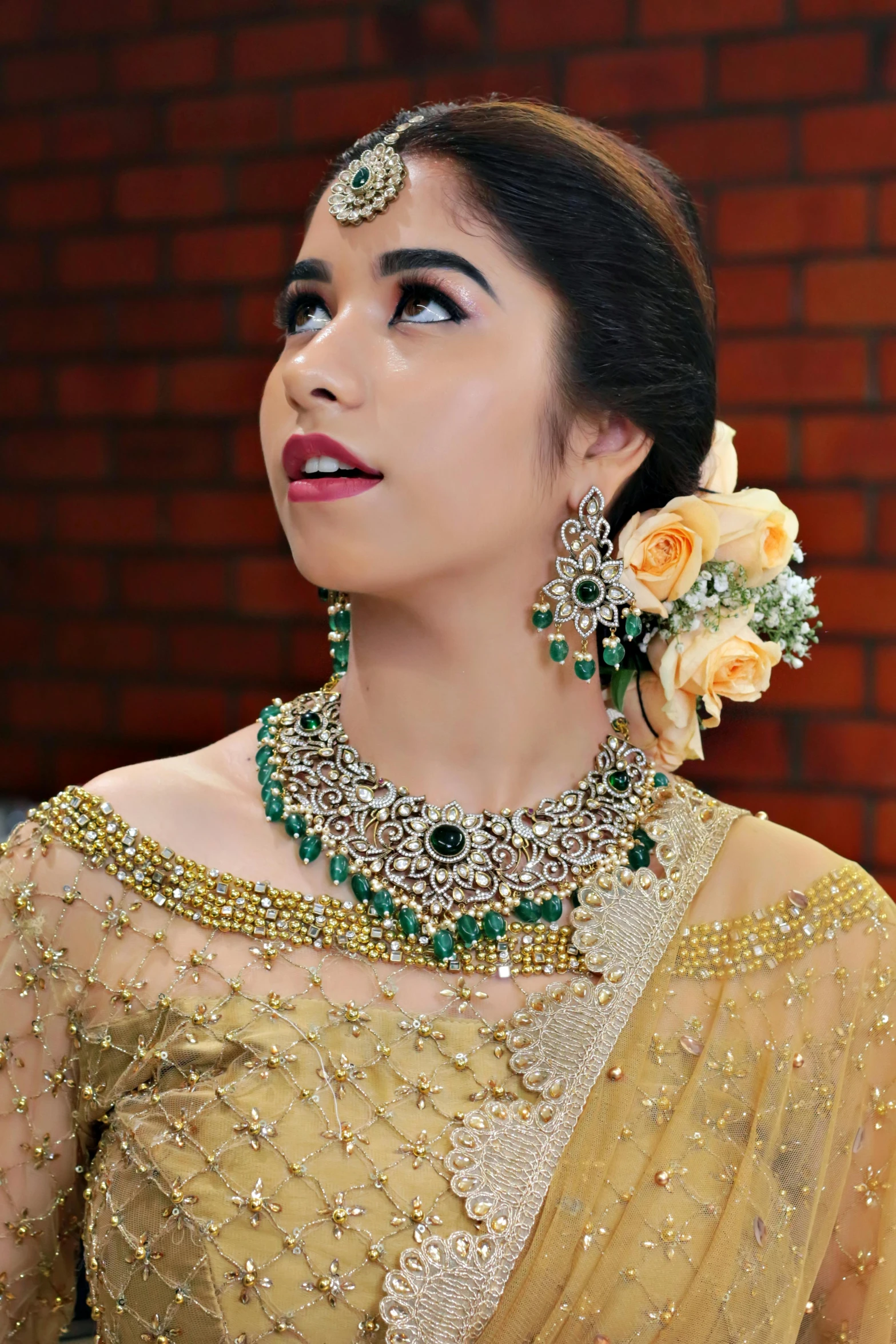 a woman in a gold outfit with roses and necklaces