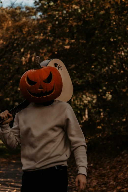 a boy is walking on the street dressed in a pumpkin mask