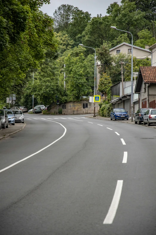 cars are traveling on a small street near buildings