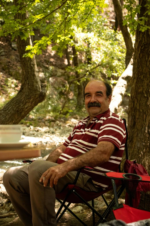 a man sits under a tree with a backpack on his lap