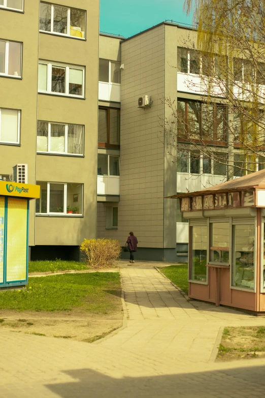 a tall building next to a walkway in front of a grassy area