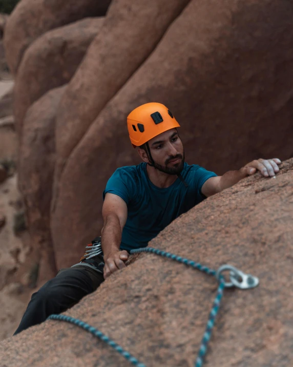 a man on a rock climbing while holding on to his hand