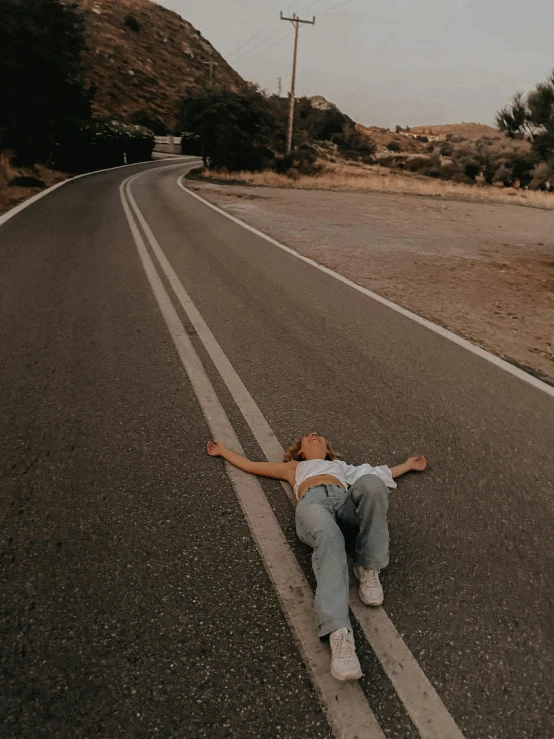 a girl laying on the side of the road