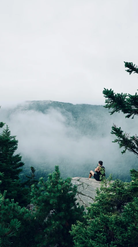 a man that is sitting on top of a cliff