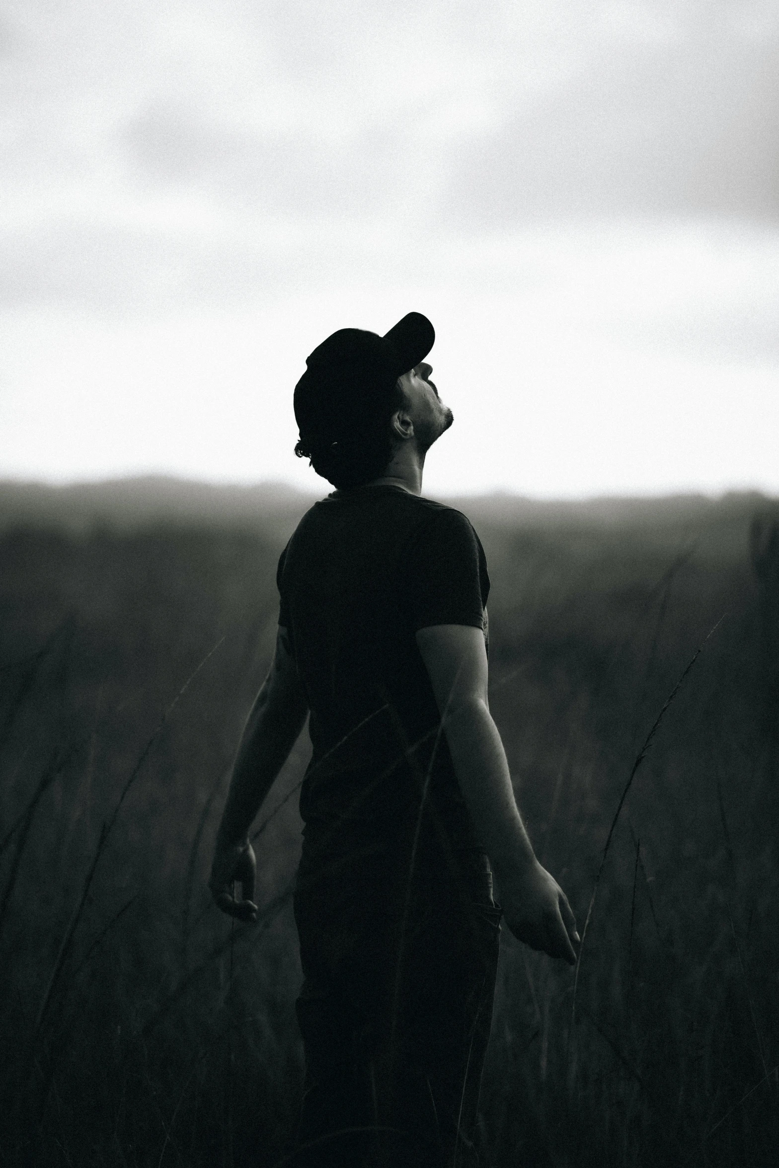 black and white pograph of young man with hat looking down