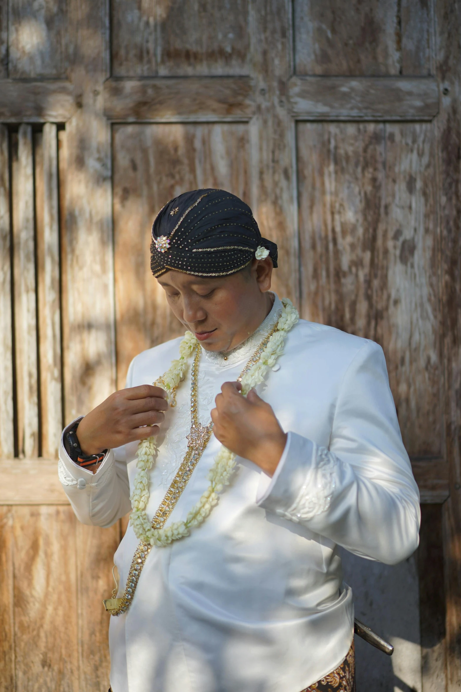 the young woman in a white blouse is wearing a lei and a black hat